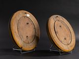 pair of wooden clock faces on stands against a black background