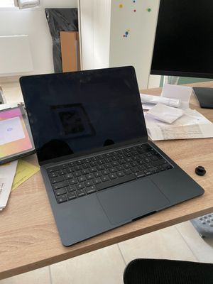un ordinateur portable posé sur un bureau en bois, devant un écran