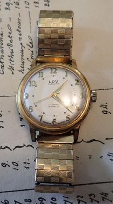 une montre posée sur une feuille de papier, sur une table