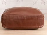 a brown leather bag sitting on top of a wooden table