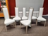 six chaises de salle à manger en cuir blanc dans une pièce avec un mur rouge en arrière-plan
