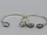 two silver bracelets and a silver ring on a white surface