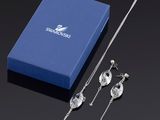 une boîte bleue sur laquelle sont posés un collier et des boucles d'oreilles argentés