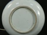 a close up of a white and blue vase on a black surface
