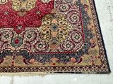 a red and gold rug on the floor next to a black and white cat