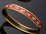 two bangles with red and white designs on them on a black surface