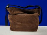 un sac à main en daim marron posé sur une table blanche