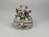 porcelain figurine of two people sitting on top of a box
