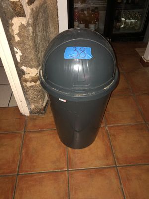une poubelle noire sur laquelle est collé un autocollant bleu