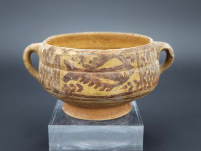 une image représentant un vase marron et jaune posé sur un socle transparent