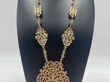 a black mannequin with a gold necklace and earrings on it