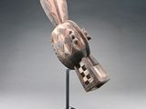 une sculpture en bois représentant un oiseau, posée sur un socle noir