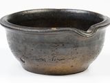 a black bowl with writing on it sitting on a white surface
