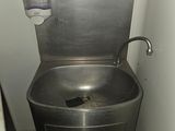 a metal sink in the corner of a small bathroom