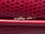 a close up of a red purse with a small hole in it