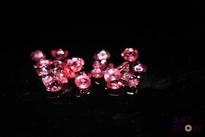 pink crystal beads on a black surface with a black background