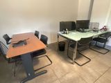 des tables et des chaises dans une pièce équipée d'un bureau et d'un ordinateur