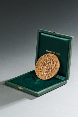 l'image d'une médaille d'or dans une boîte verte posée sur une surface grise
