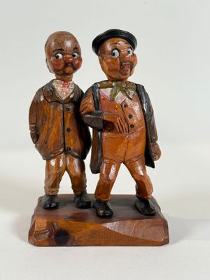 wooden figurines of two men with hats and canes on a white background