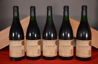 four bottles of wine are lined up on a red table