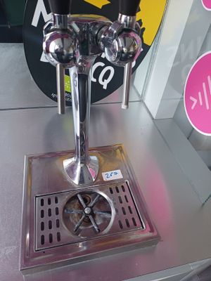 un robinet à bière posé sur une table en métal, devant une enseigne