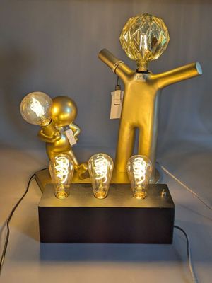 a gold statue of a man holding a light bulb and a lamp