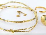 des bijoux posés sur un fond blanc, notamment un collier, une bague et un bracelet en or