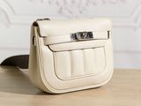 beige leather handbag on wooden table with wallpapered wall in background