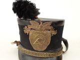 un chapeau noir orné d'un emblème doré et d'une plume