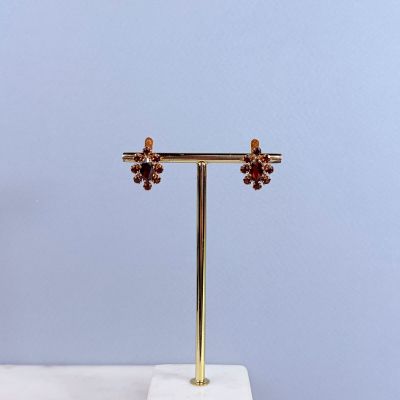 paire de boucles d'oreilles en or et grenat, posée sur un socle en marbre