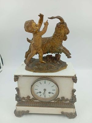 une petite horloge surmontée d'une statuette de chèvre