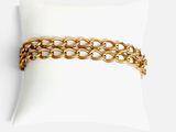 gros plan d'un bracelet en chaîne en or sur un oreiller