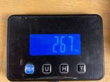 a digital clock on a table next to a cup of coffee