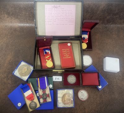 une boîte contenant des médailles, des livres et d'autres objets, posée par terre