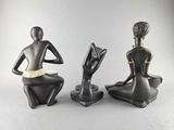 two statues of a woman sitting on their knees with their hands in the air