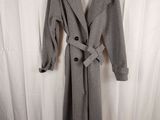 grey wool coat with belt and buttons on a hanger in front of a white curtain