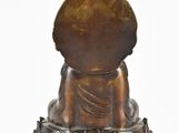 bronze statue of a person sitting in a lotus position on a white surface
