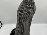 la semelle d'une paire de chaussures noires sur une surface blanche