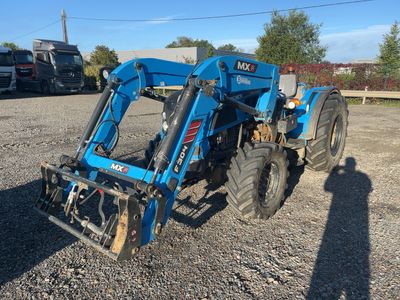 un tracteur bleu garé sur un terrain en gravier