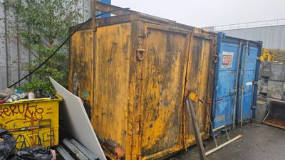 a yellow dumpster sitting next to a blue dumpster