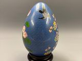 an egg with a dragonfly painted on it sitting on a stand
