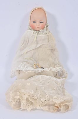 an old doll with a white dress and bonnet sitting on a white surface
