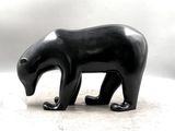 une sculpture noire représentant un ours sur une surface blanche