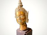 statue of a woman ' s head with a golden crown on top of a wooden block