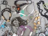 many different necklaces and bracelets laid out on a table