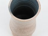 a close up of a small vase on a white surface