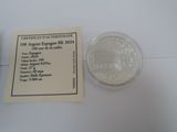 a silver coin sitting next to a certificate on a table