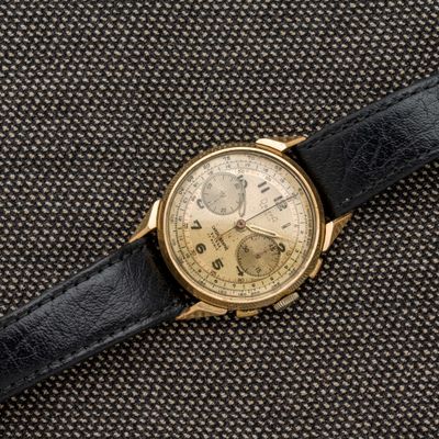 un gros plan d'une montre en or avec un bracelet en cuir noir