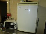 a small white refrigerator and a microwave on a counter