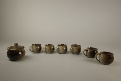 six tasses et une théière sont alignées en rang